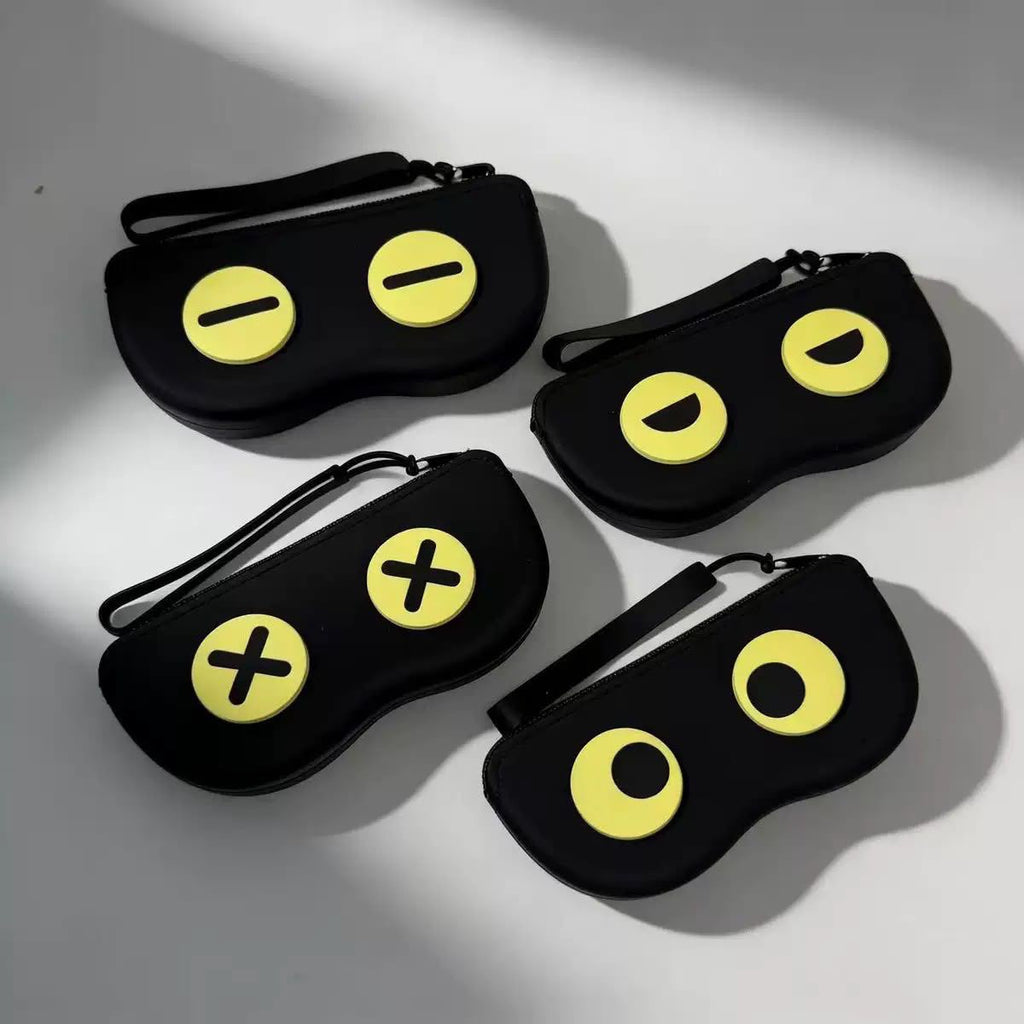 Four black protective phone cases with yellow cartoon eye details, arranged on a light gray surface with soft shadows.